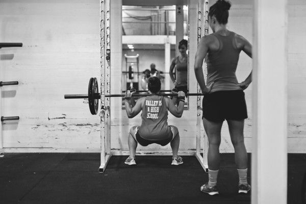 Persoon die een squat-oefening uitvoert om de benen te trainen en sterker te maken.